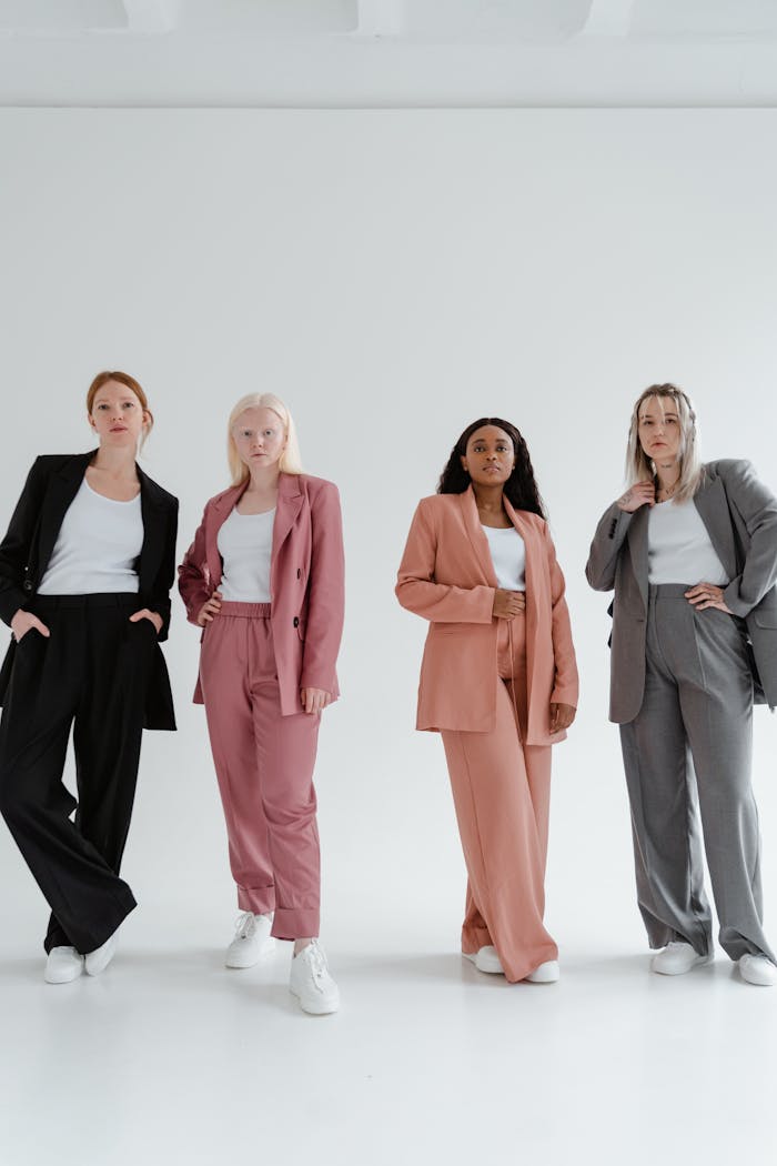 A group of confident women posing in colorful suits on a white background.